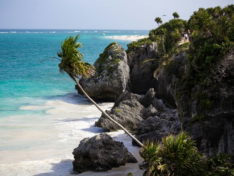 Playa y acantilados de Tulum con palmeras sobre el mar turquesa